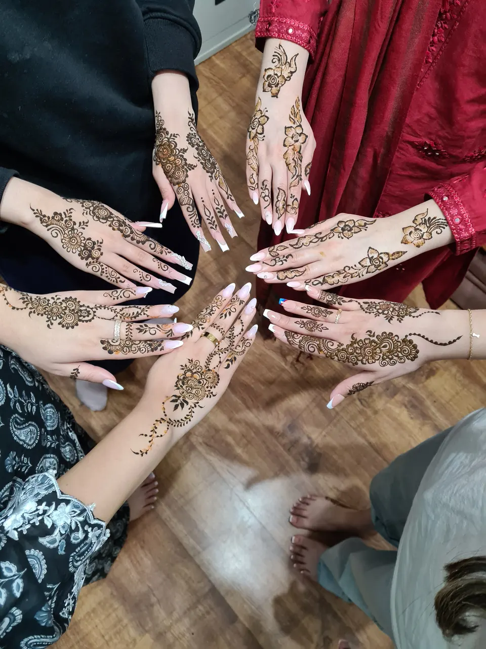 Mehndi party guests showing floral Arabic henna in a circle